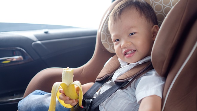 toddler eating banana in car seat